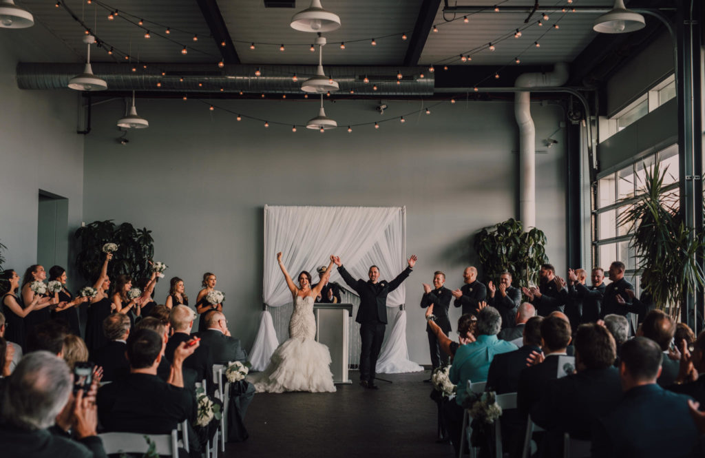 Couple raising arms in celebration at the end of their ceremony.