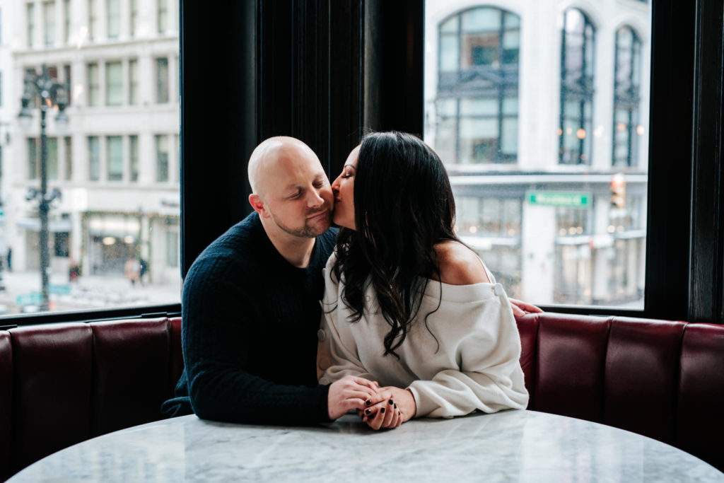Woman kissing man on the cheek during their engagement session.