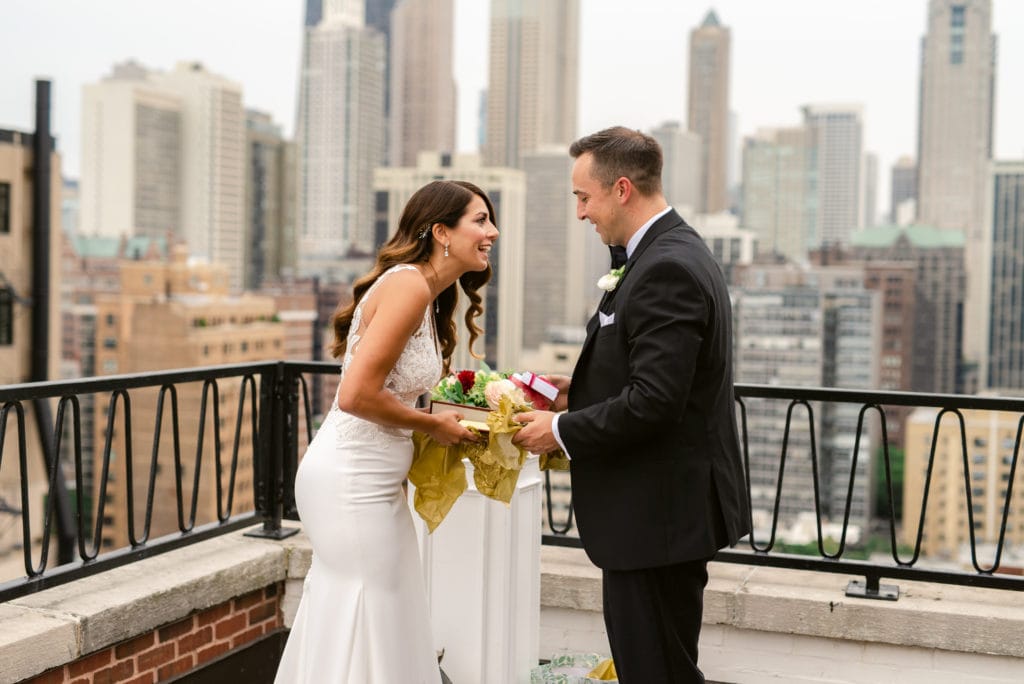 Couple standing on top of the Ambassador Hotel in Chicago, exchanging gifts during their first look.