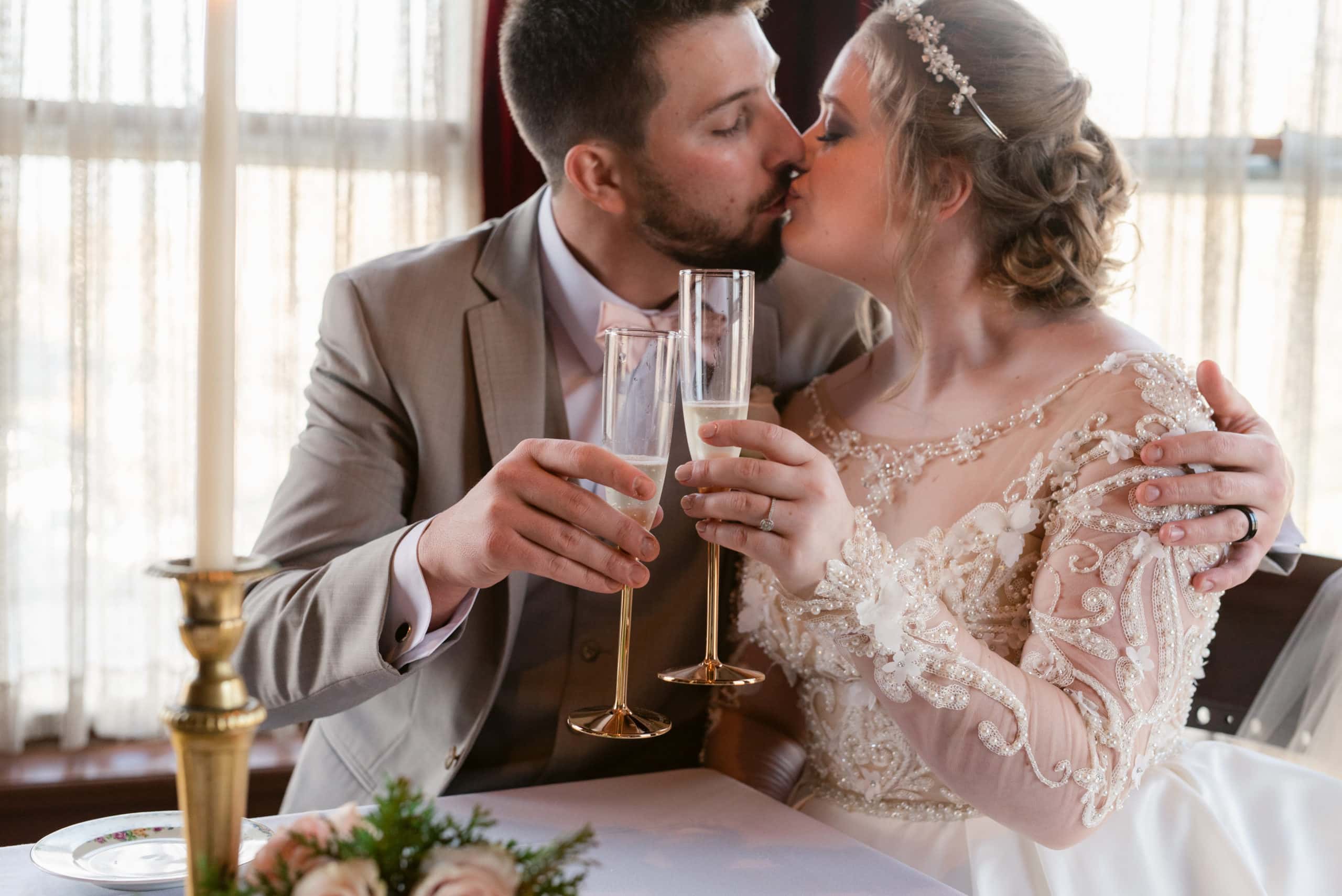 couple kissing, toasting glasses during their wedding reception