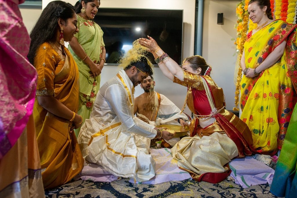 Bride pours rice on grooms head during telagu ceremony.