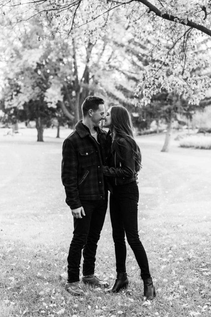 newly engaged couple kissing under a tree during their fall proposal session.