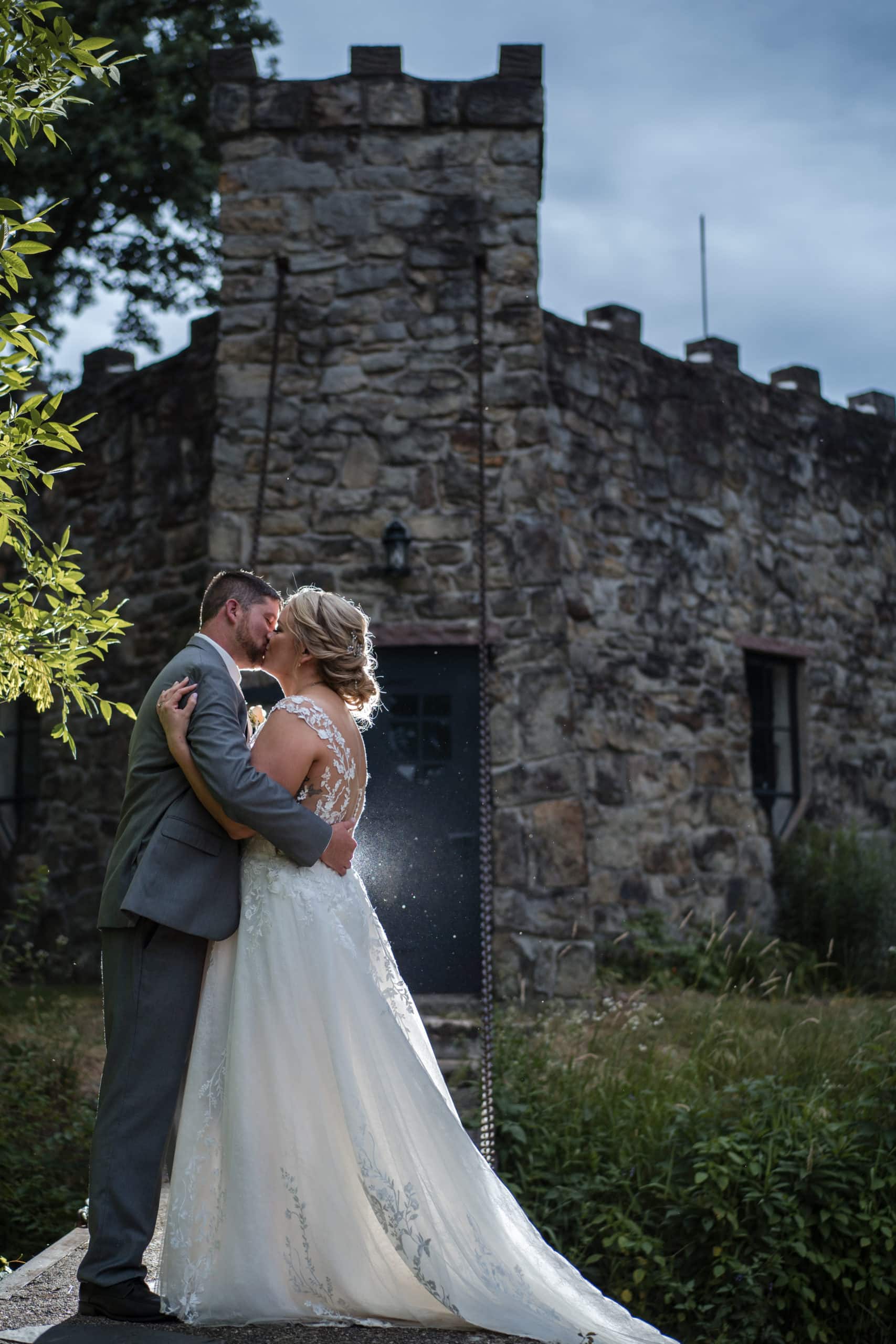 Bride and Groom kissing in front of a castle at Wilder Creek Nature center.