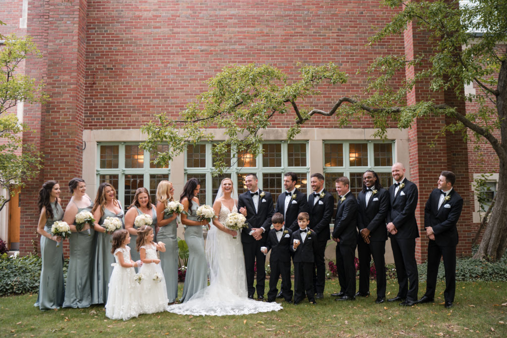 Michigan couple standing and laughing with their wedding party at the MSU Chapel in East Lansing.